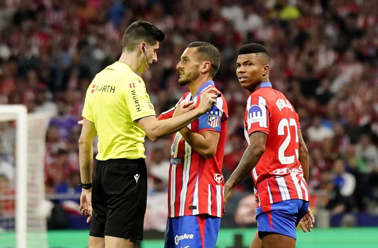El árbitro Mateo Busquets Ferrer charlando con Koke, capitán del Atlético de Madrid, antes de parar el partido.