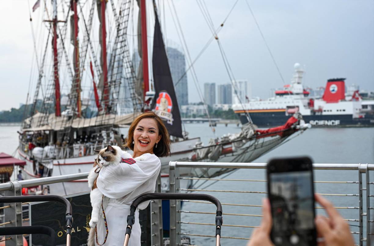 La felicidad de los felinos también la gozan sus dueños, puesto que hasta posan para fotografiarse en su recorrido por Singapur.