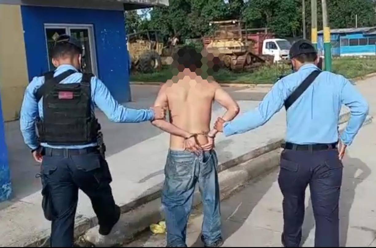 Momento en que agentes ingresan al sospechoso del crimen de su madre a una posta policial de Yoro. 