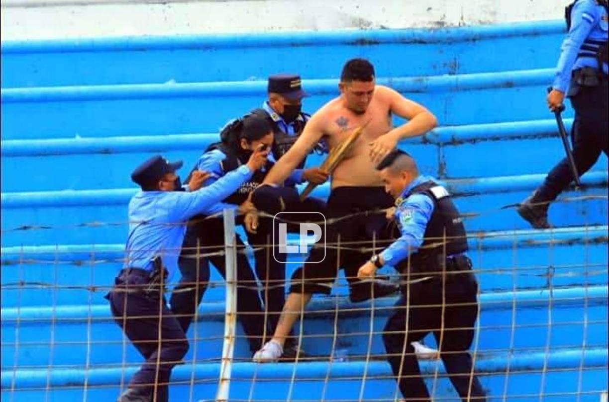 Elementos policiales tratando de detener a este aficionado en las gradas del estadio Olímpico.