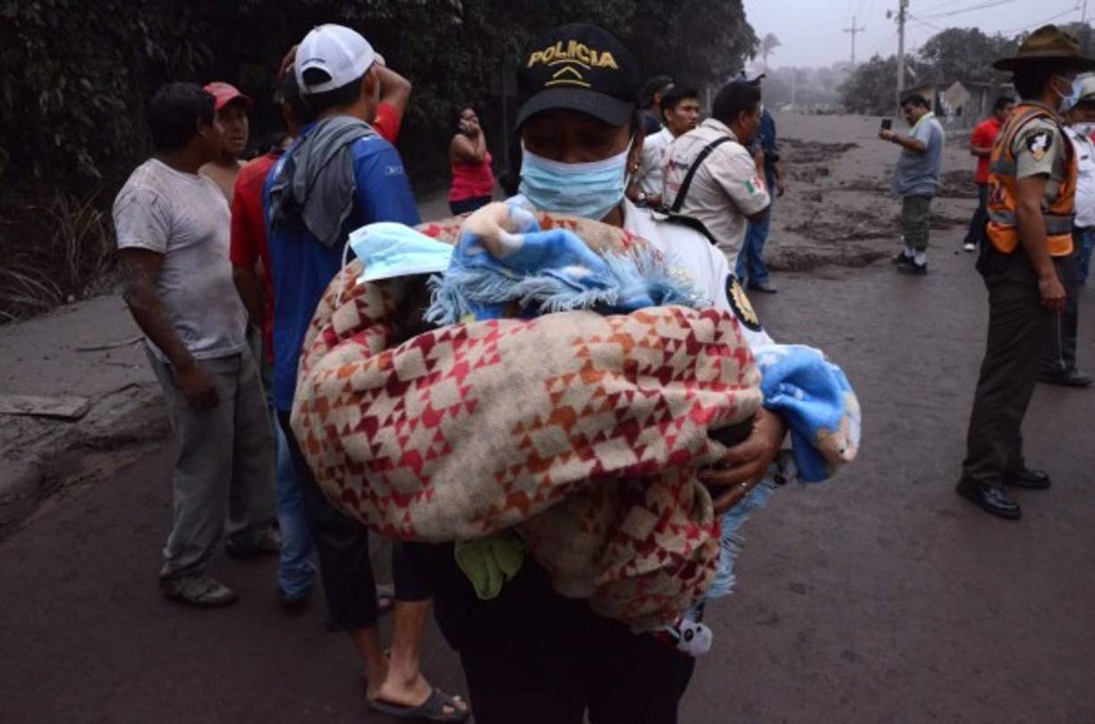 Un oficial de Policía rescata a un bebé tras la erupción. / AFP PHOTO / NOE PEREZ