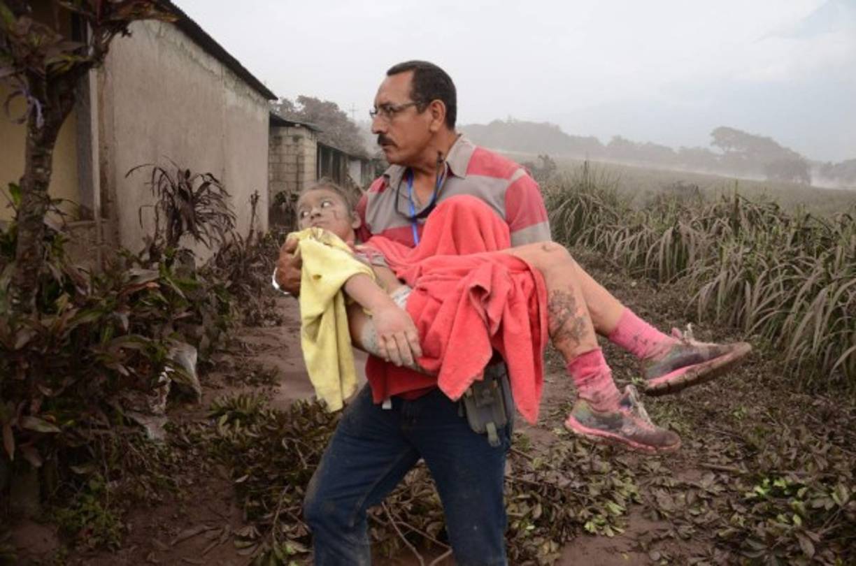 GU7080. EL RODEO (GUATEMALA), 03/06/2018.- Un hombre ayuda a una niña afectada en El Rodeo, Escuintla (Guatemala) hoy, domingo 3 de junio de 2018, luego de la erupción del volcán de Fuego, que ha dejado al menos 25 muertos, 20 heridos y más de 1,7 millones de personas afectadas. EFE/NOE PÉREZ