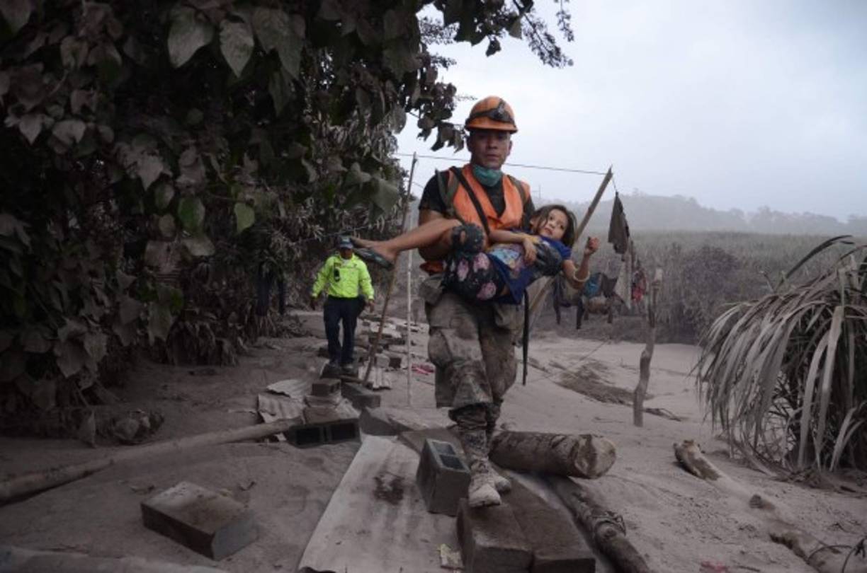 Un trabajador de los equipos de rescate de Guatemala ayuda a una niña en El Rodeo, Escuintla (Guatemala). EFE/NOE PÉREZ<br/>
