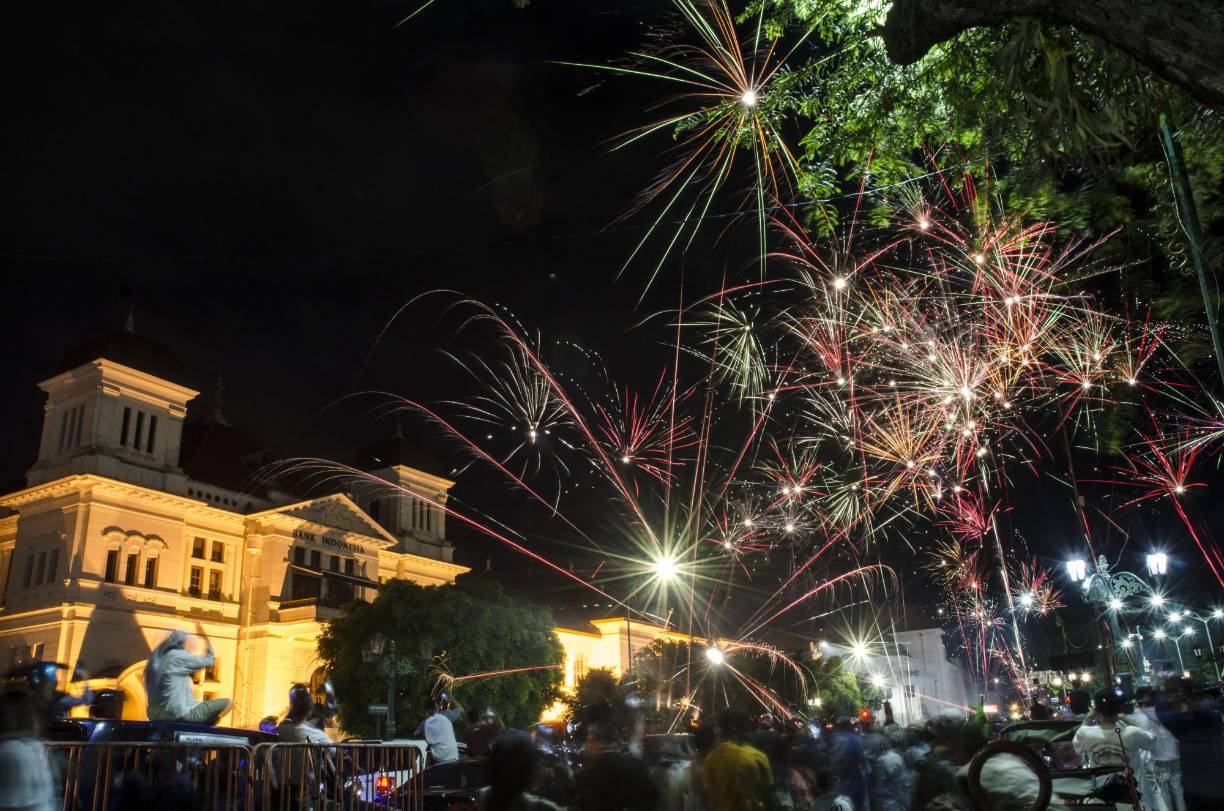 Miles se reúnen en la plaza del pueblo mientras los fuegos artificiales se disparan durante las festividades de la víspera de Año Nuevo en Yogyakarta el 1 de enero de 2022.