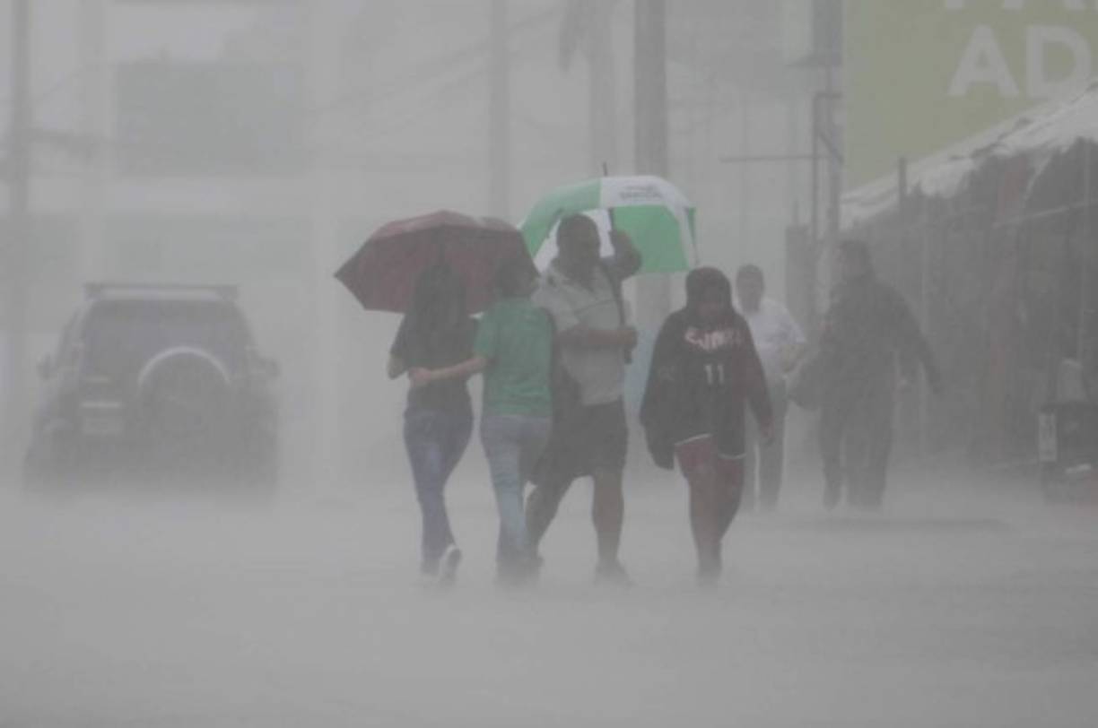 Algunas personas intentan protegerse de la lluvia.