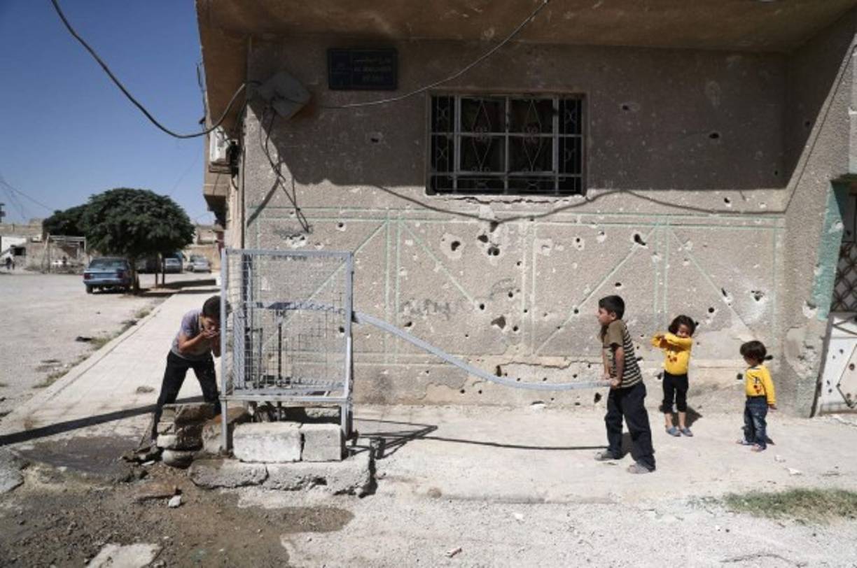 Un grupo de niños juega frente a un pozo de agua en la ciudad de Alepo.
