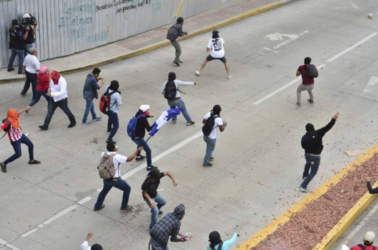 Decenas de emcapuchados lanzaron piedras contra la Policía Nacional que respondió con gases lacrimógenos.