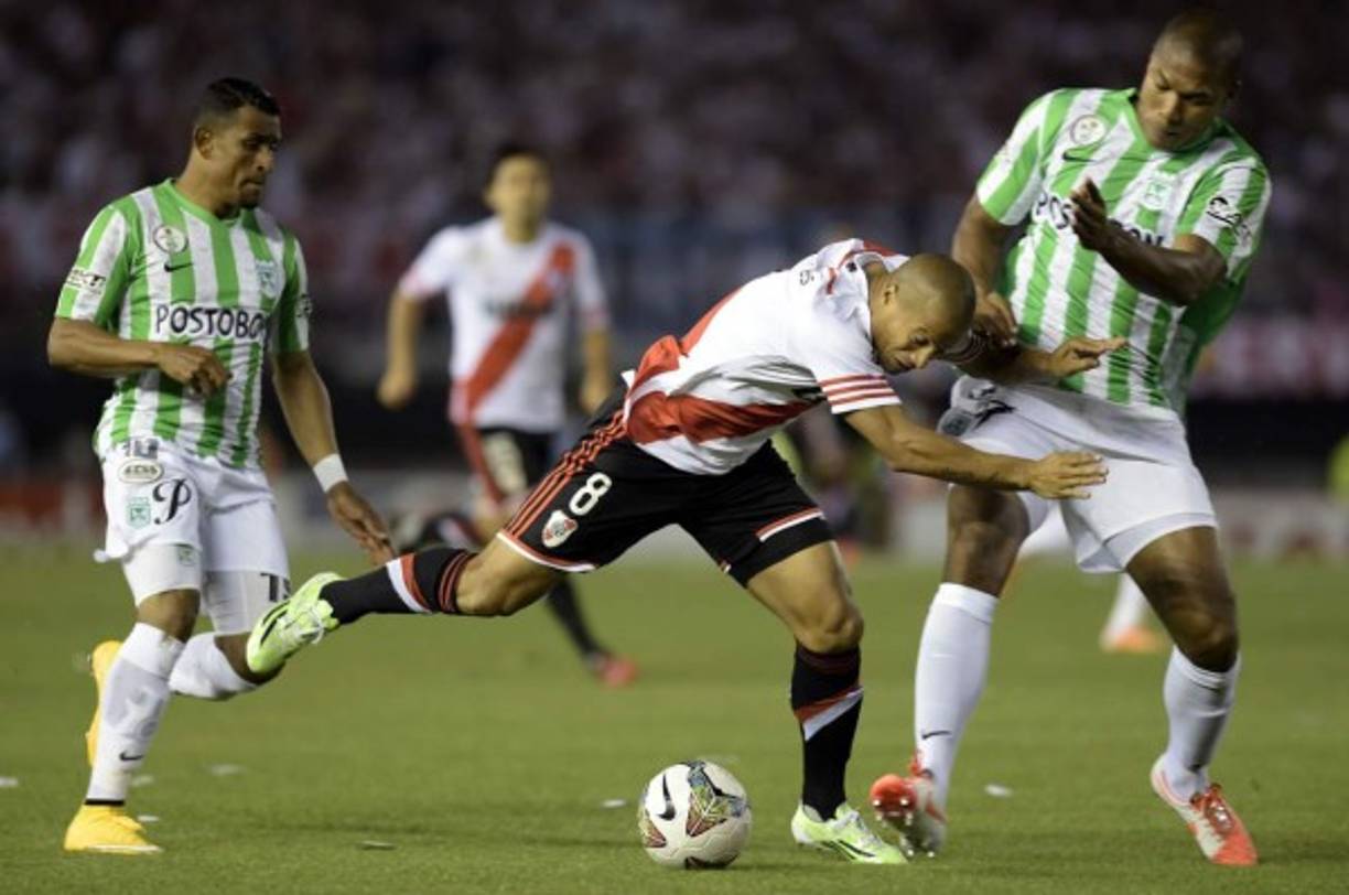 Carlos Sanchez de River Plate lucha por el balón con los defensores del Atlético Nacional, Alexis Henríquez (derecha) y Farid Díaz.