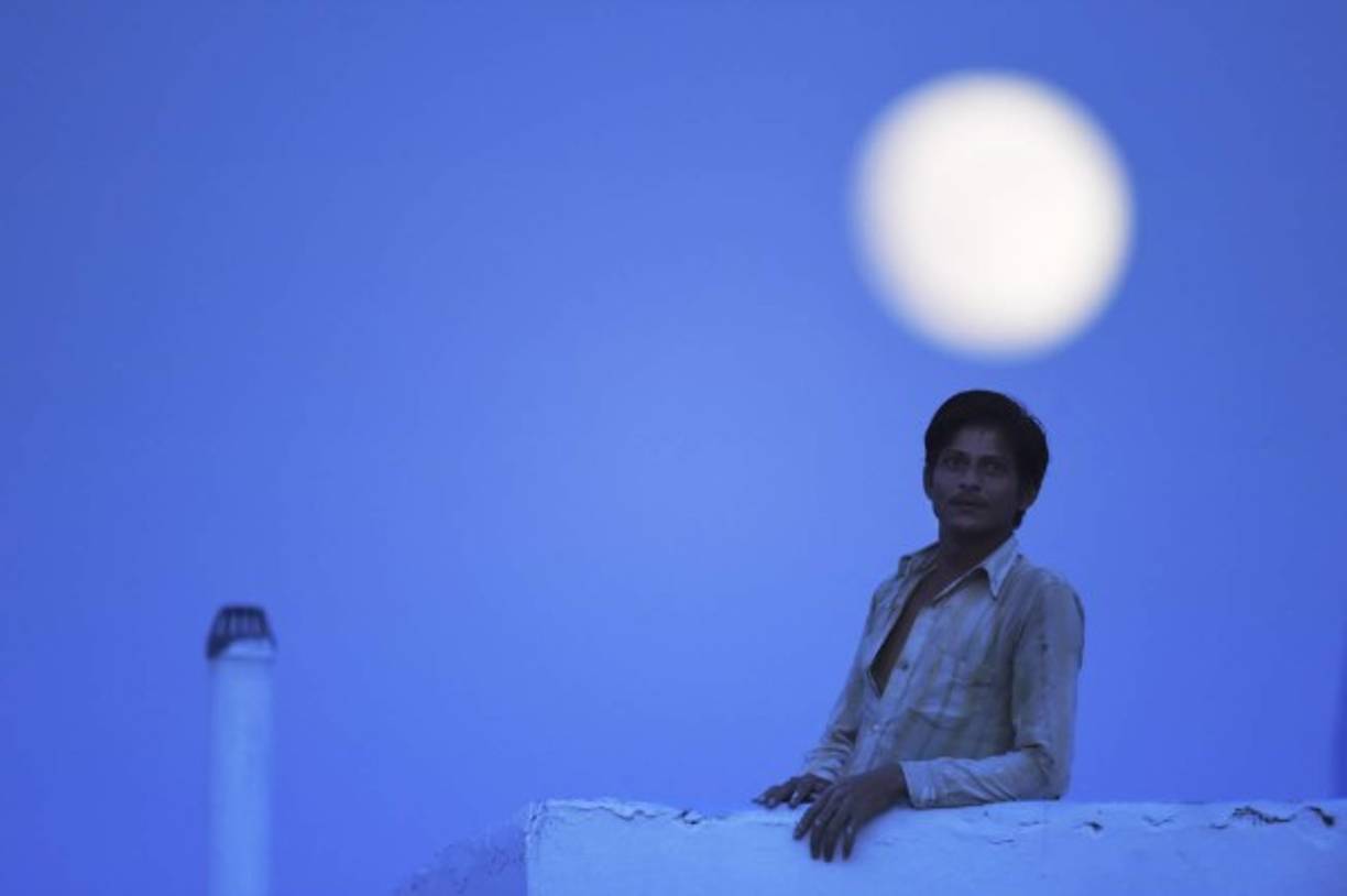 Un hombre en Nueva Delhi, India aparece con la luna llena como telón de fondo.