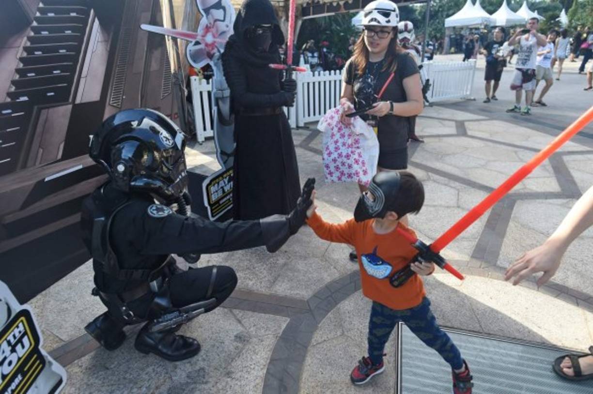 Un pequeño aprendiz de Lord Sith choca la mano con otro entusiasta de Star Wars.
