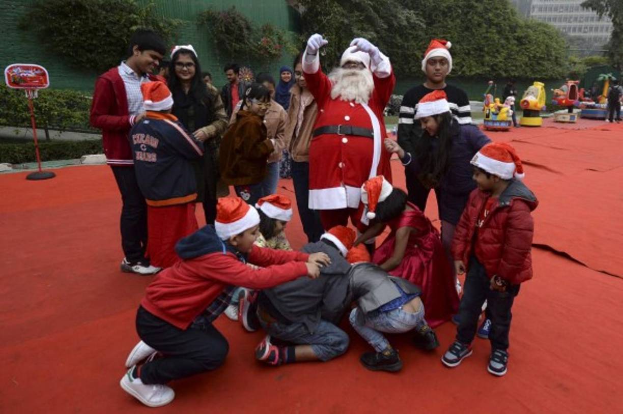 Un hombre vestido con un traje de Papá Noel regala chocolates a los niños durante una fiesta de Navidad en Dhaka, capital de Bangladesh.