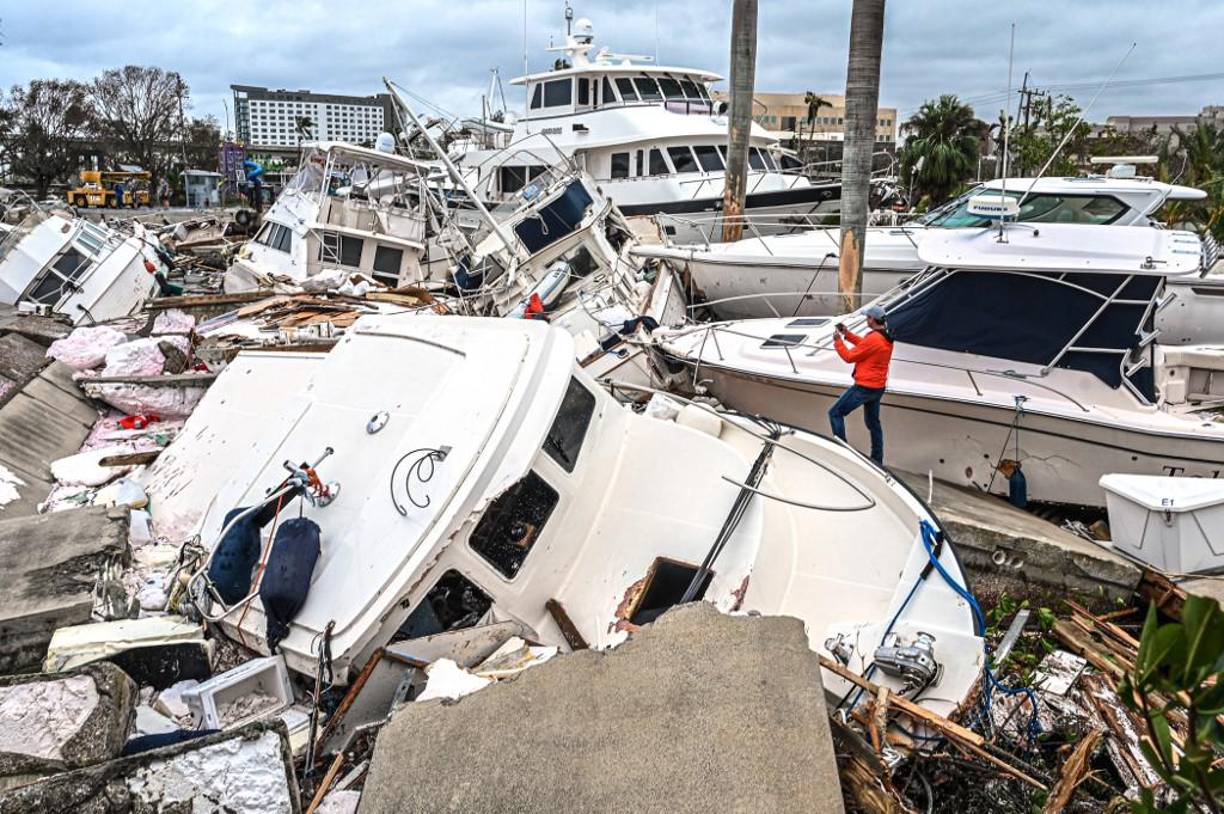 Un hombre toma fotos de los barcos dañados por el huracán Ian en Fort Myers, Florida. El huracán dejó gran parte de la costa suroeste de Florida en la oscuridad el jueves temprano, provocando inundaciones “catastróficas” que obligaron a los funcionarios a prepararse para una gran respuesta de emergencia. 