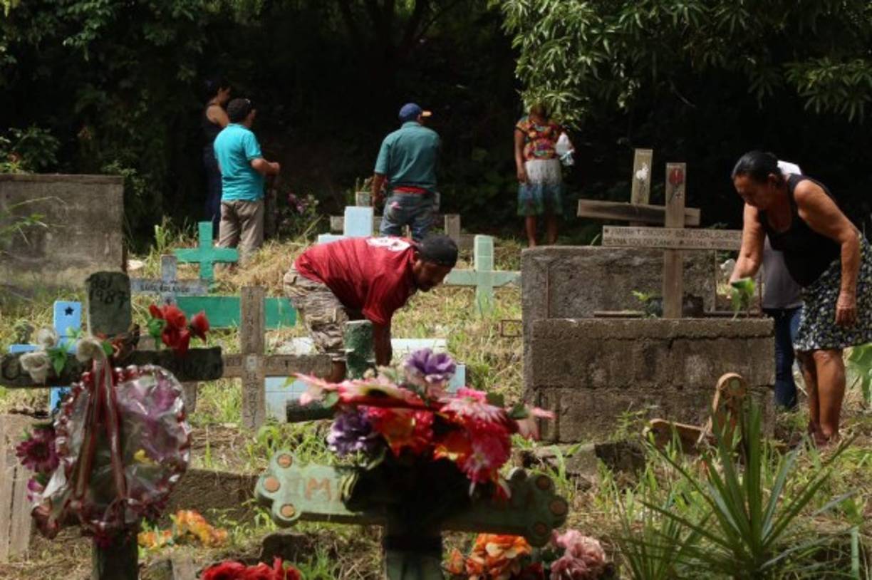 Varias personas limpian las tumbas de sus familiares y les ponen flores en el cementario La Puerta de San Pedro Sula.