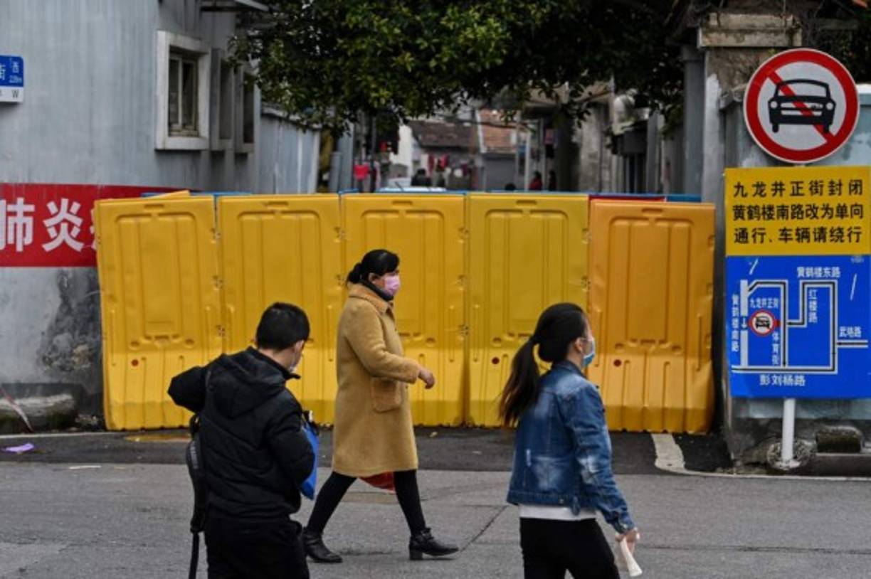 Vendors wearing face masks wait for customers at their meat stall in Wuhan in China's central Hubei province on April 18, 2020. (Photo by Hector RETAMAL / AFP)
