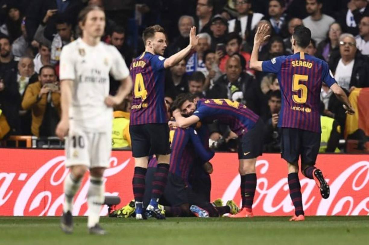 Luka Modric no podía creer la derrota del Real Madrid ante Barcelona. Al fondo, los jugadores del club catalán festejando el 0-2 parcial.