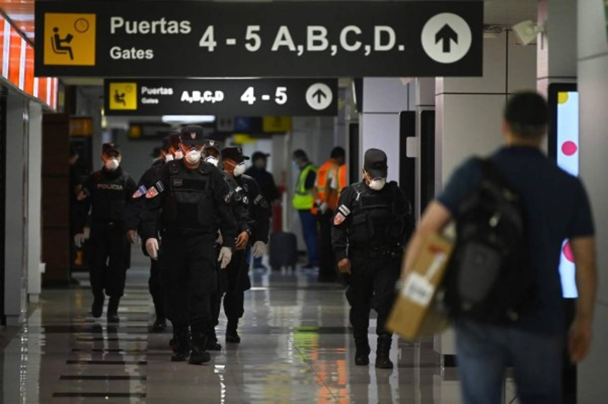 Members of the Police's Maintenance Unit at San Oscar Romero International Airport in San Luis Talpa, El Salvador, wear face masks as a precaution against the spread of the new coronavirus, the COVID-19, on March 12, 2020. - El Salvador banned entry to all foreigners for a period of 21 days in a bid to curb the spread of the coronavirus, the Central American country's president announced on March 11. (Photo by Marvin RECINOS / AFP)