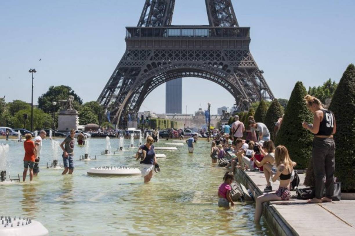 FRANCIA. Chapuzón por ola de calor. Un grupo de personas se refrescan en las fuentes de los jardines del Trocadero junto a la Torre Eiffel en París.