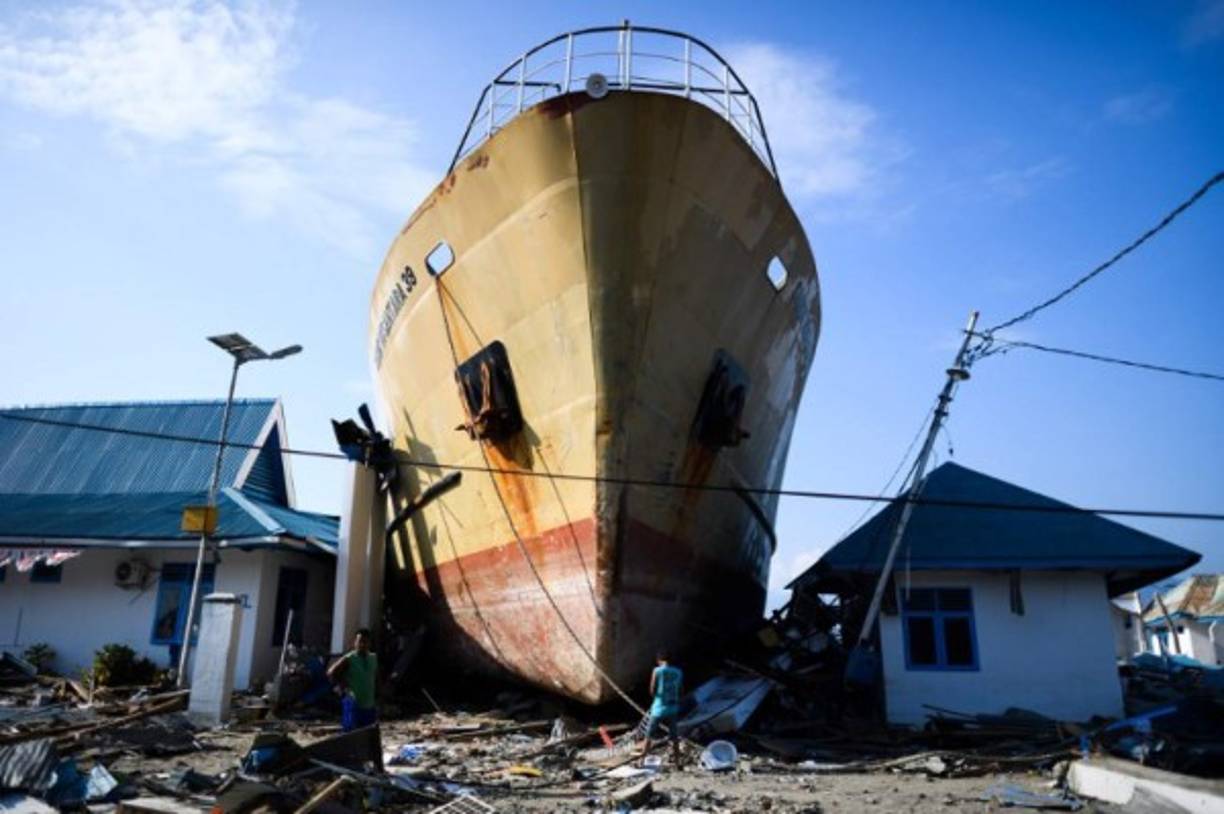 -- AFP PICTURES OF THE YEAR 2018 --<br/><br/>Quake survivors make their way past a washed out passenger ferry in Wani, Indonesia's Central Sulawesi on October 3, 2018, after an earthquake and tsunami hit the area on September 28. - Nearly 1,400 people are now known to have died in the quake-tsunami that smashed into Indonesia's Sulawesi island as UN officials warned the 'needs remain vast' for both desperate survivors and rescue teams still searching for victims. (Photo by JEWEL SAMAD / AFP)