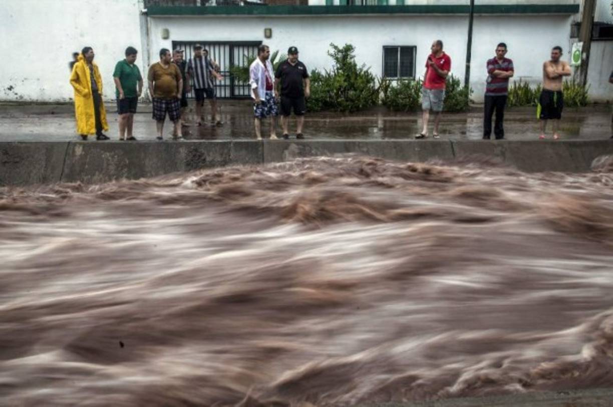 Imágenes en video tomadas por pobladores de la zona mostraban como la corriente de agua y tierra arrastraba coches, árboles y toda clase de escombros.