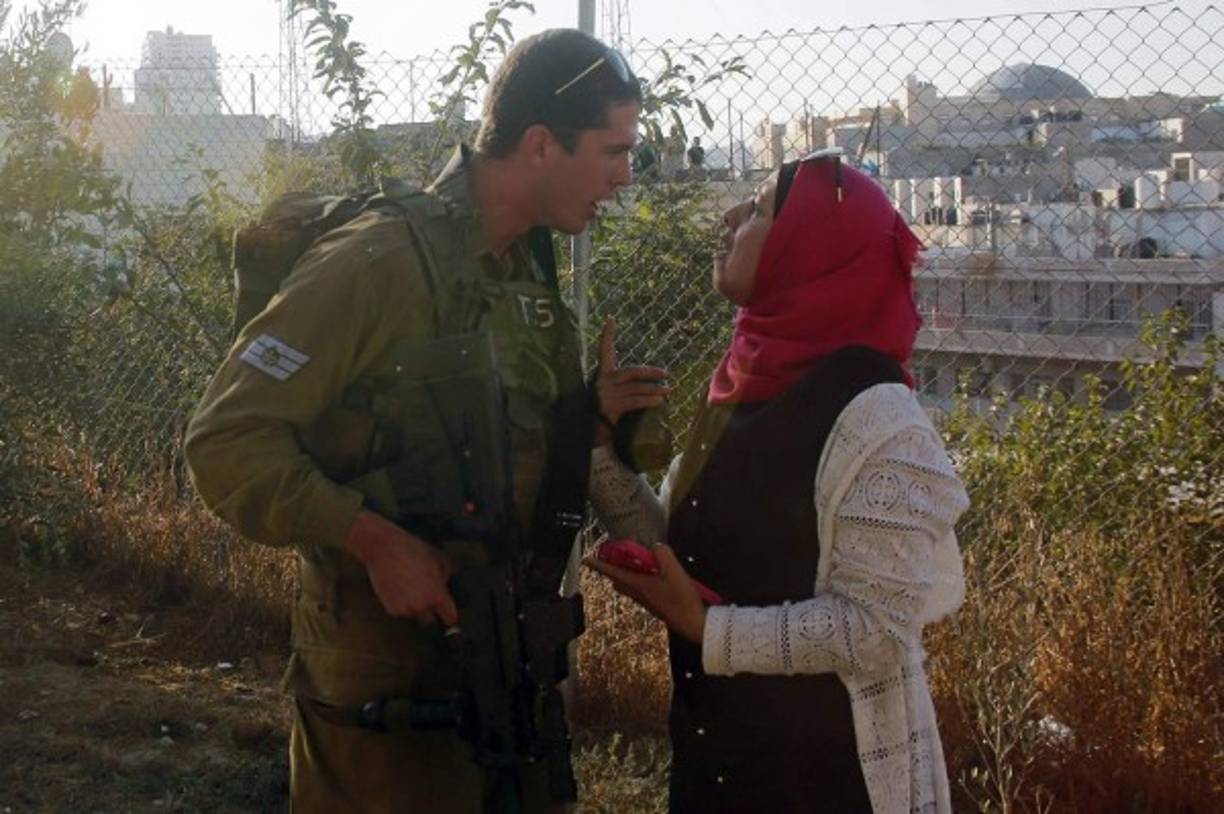 HEBRÓN. Enfrentamiento cara a cara. Una mujer discute con un miembro de las fuerzas de seguridad israelíes en al lugar donde un palestino fue tiroteado tras atacar a un soldado israelí. Foto: EFE/Abed Al Hashlamoun