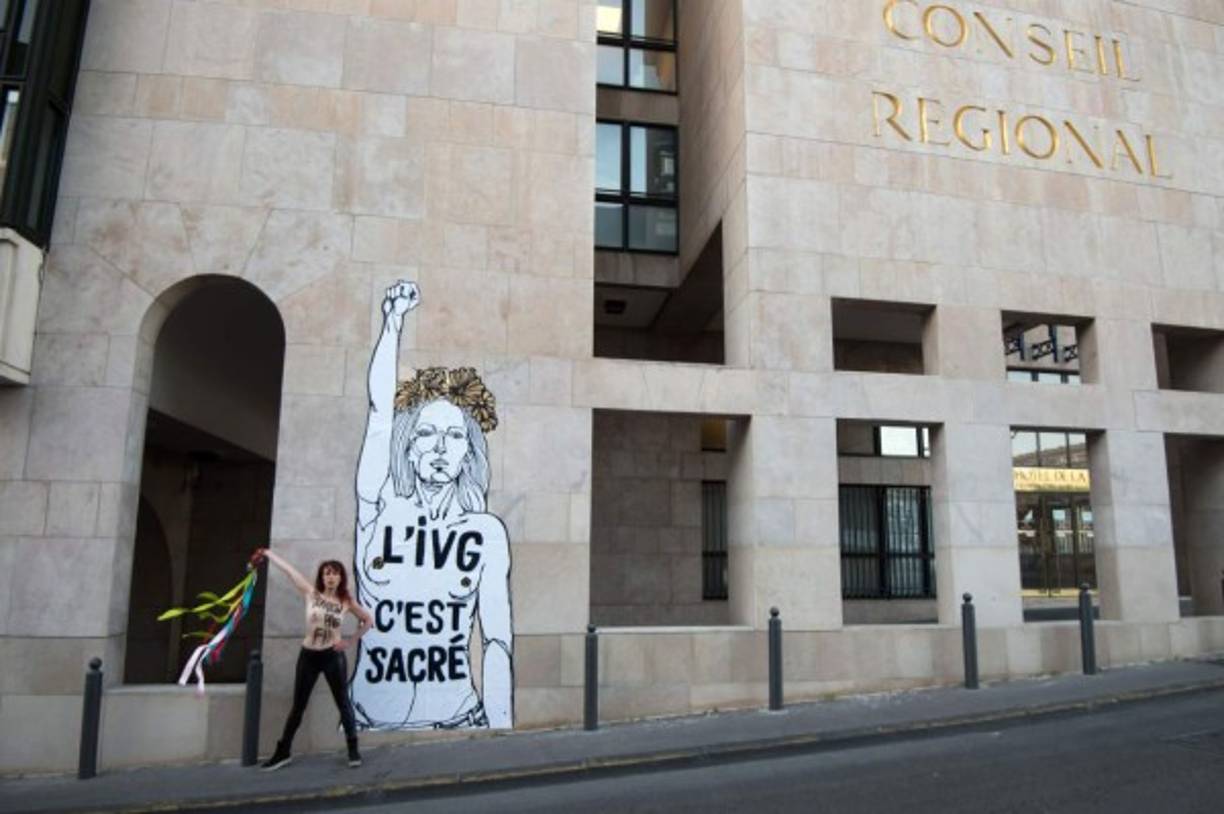 Una activista de Femen protesta con el torso desnudo frente a la obra de un artista frances que denuncia 'el aborto es sagrado'.