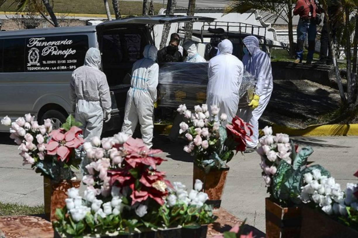 Trabajadores de una funeraria cargan el ataúd con los restos del periodista hondureño Nelson Flores Valeriano. AFP