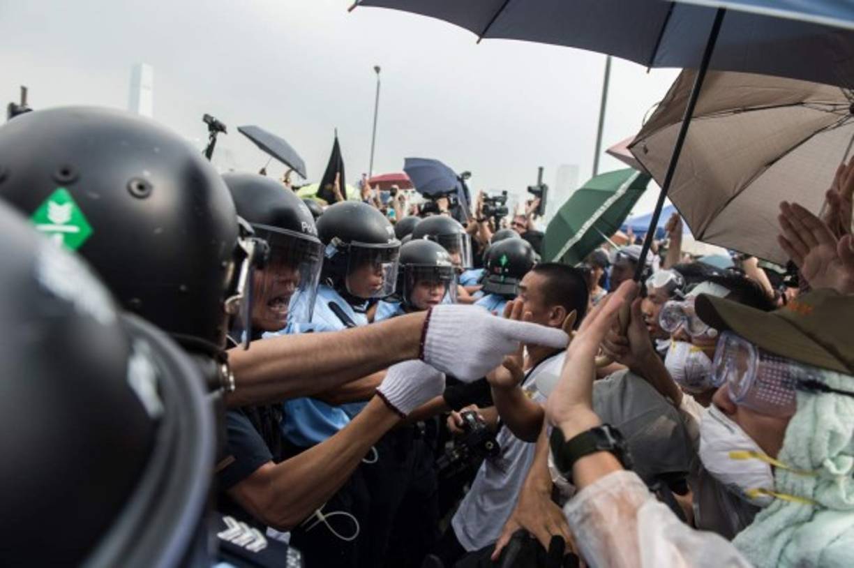 Policía forman una línea para dar paso a una ambulancia mientras los manifestantes pro-democracia gritan consignas frente a la sede del gobierno en Hong Kong el 3 de octubre de 2014. AFP