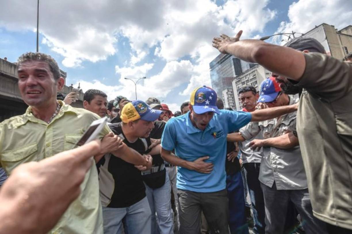 Venezuelan opposition leader and former presidential candidate Henrique Capriles (C) reacts to tear gas shot by the police during protests against the government of President Nicolas Maduro on April 6, 2017 in Caracas.<br/>The center-right opposition vowed fresh street protests - after earlier unrest left dozens of people injured - to increase pressure on Maduro, whom they blame for the country's economic crisis. / AFP PHOTO / JUAN BARRETO