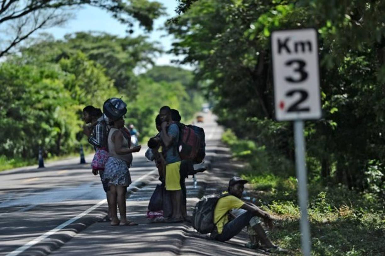 Los migrantes africanos y haitianos permanecen al costado de una carretera después de pasar por un 'cruce ciego' de Nicaragua a Honduras en su camino a los Estados Unidos, en Guasaule, Honduras.