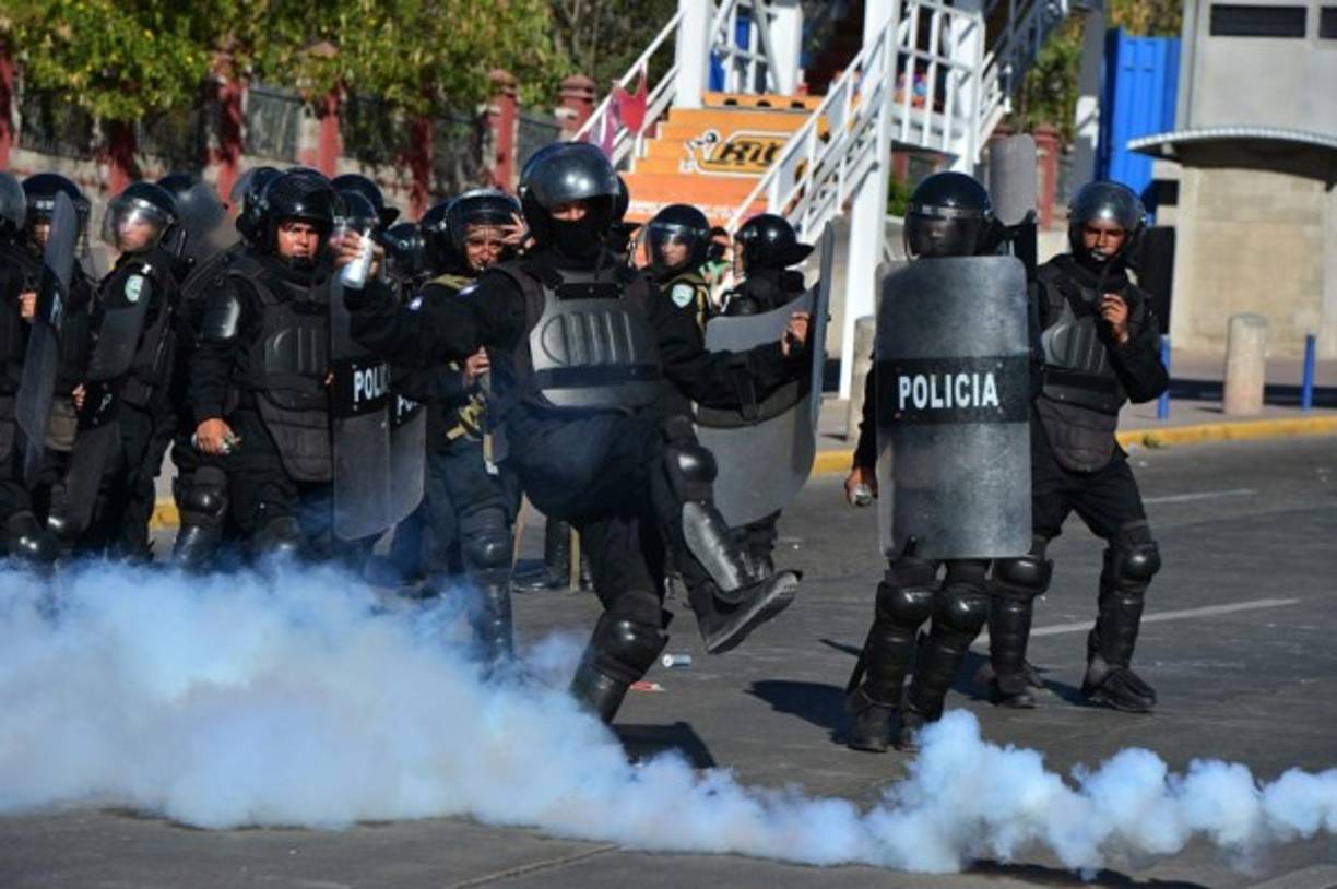Momento en que un policía antimotín lanza una bomba lacrimógena contra los estudiantes.