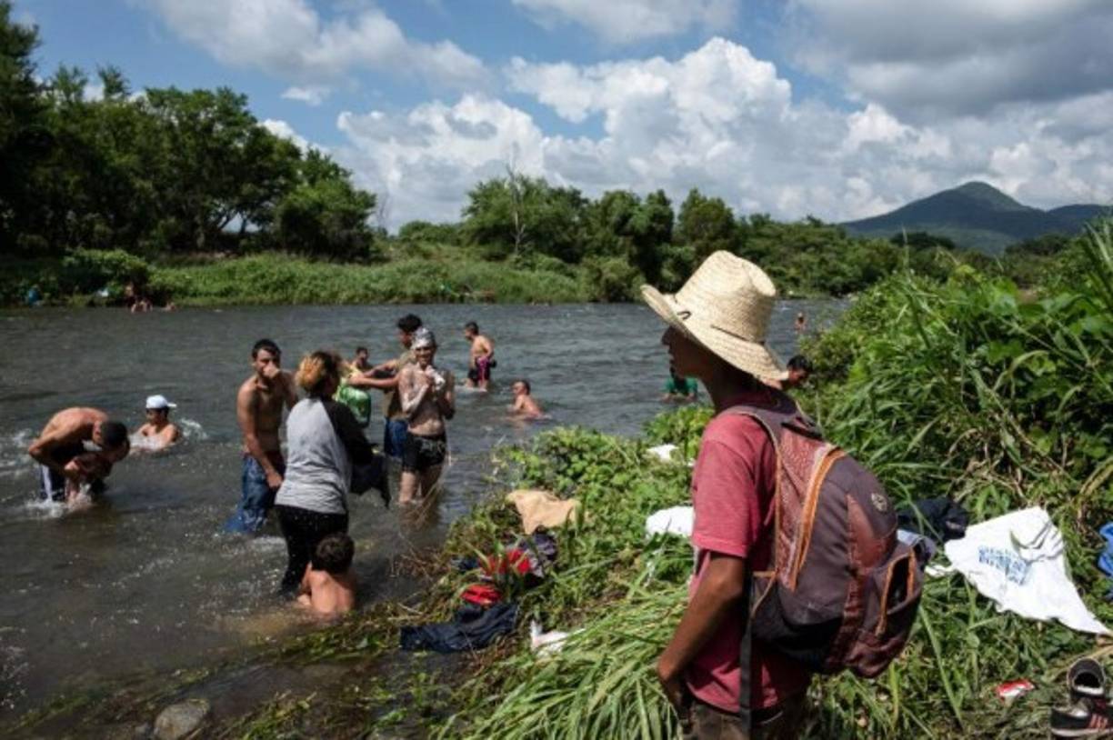 Los inmigrantes hondureños que participan en una caravana que se dirige a los Estados Unidos, lavan la ropa y se bañan en un río en Pijijiapan, estado de Chiapas, México.