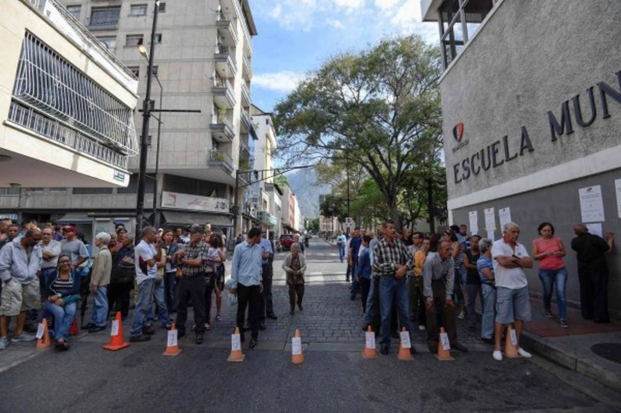 Venezolanos hacen fila frente a una mesa de votación mientras esperan emitir su voto durante las elecciones presidenciales en Caracas. AFP