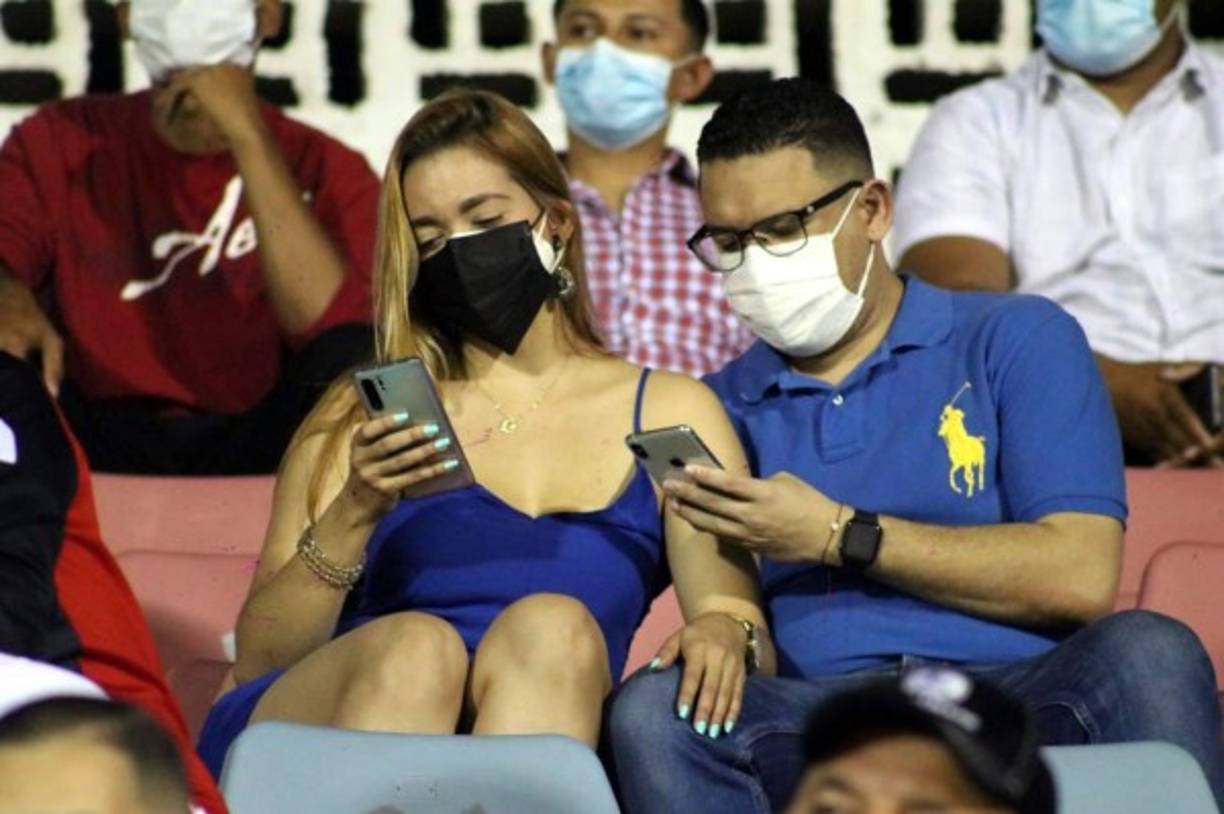 Esta pareja de aficionados, entretenidos con sus celulares en el partido Victoria-Olimpia.