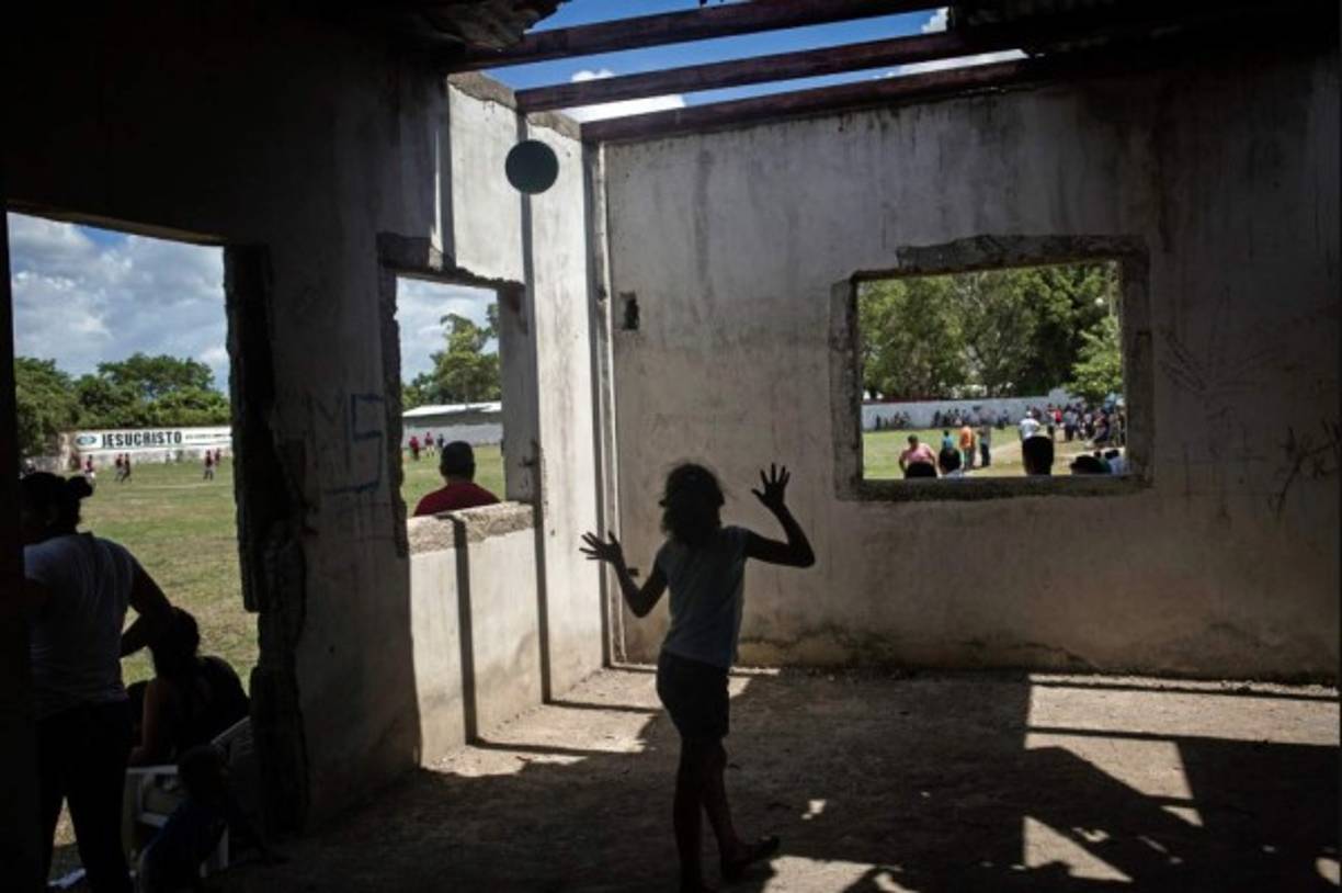 Honduras. Escapan de la violencia. The New York Times destacó en su resumen de mejores fotos del año esta imagen captada en la Rivera Hernández, que muestra a adultos jugando al fútbol en una cancha y a una niña saltando en el interior de una casa abandonada. El reportaje destacó la labor de prevención de la violencia en Honduras con la cooperación de EUA que este año costó entre $95 y 110 millones.