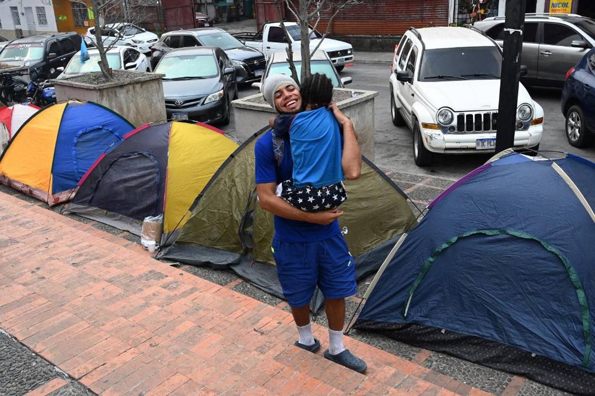 Un migrante venezolano yace con un perro en una carpa mientras espera con otros afuera del Banco Central de Honduras para retirar dinero para continuar su viaje a los Estados Unidos.