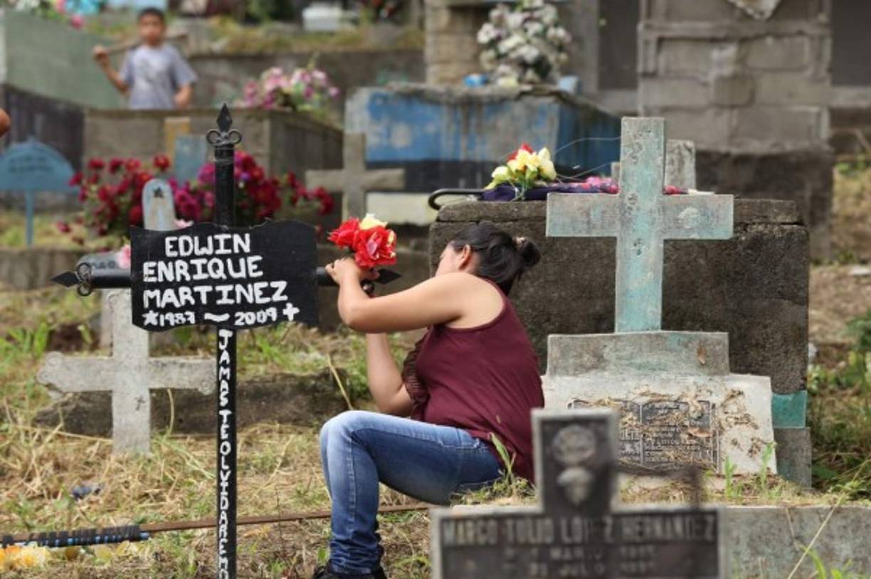 Una hondureña coloca flores en una tumba del cementario La Puerta.