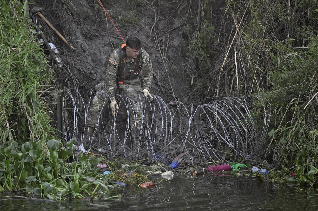 Los militares desplegaron alambre de púas en las orillas del río para prevenir el ingreso de los migrantes que les gritaban que por favor les permitieran el paso desde el lado mexicano.