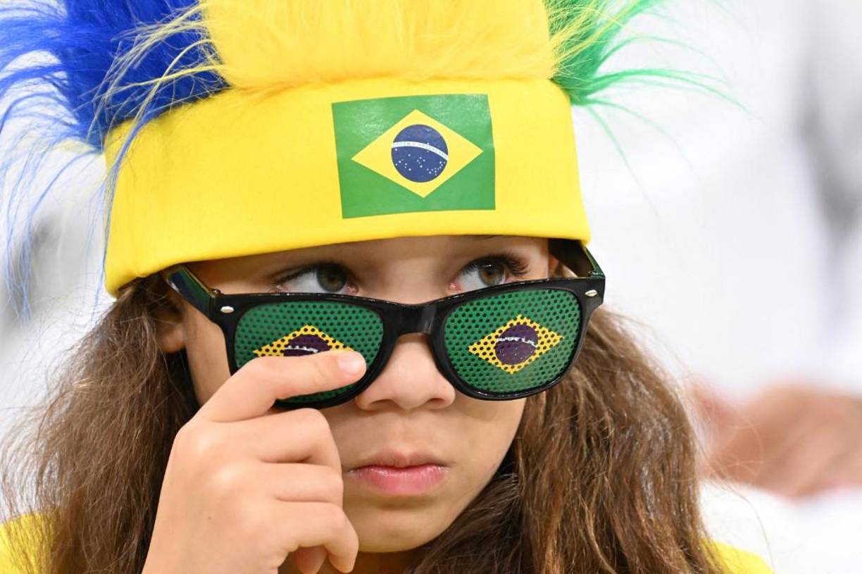 Una chica observa de reojo son sus lentes con la bandera de Brasil.