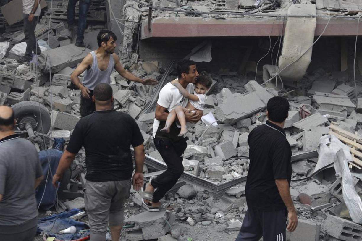  Un palestino lleva a un niño rescatado de la casa de la familia Tattari, que fue destruida en un ataque aéreo israelí en la ciudad de Gaza el 9 de octubre de 2023. 
