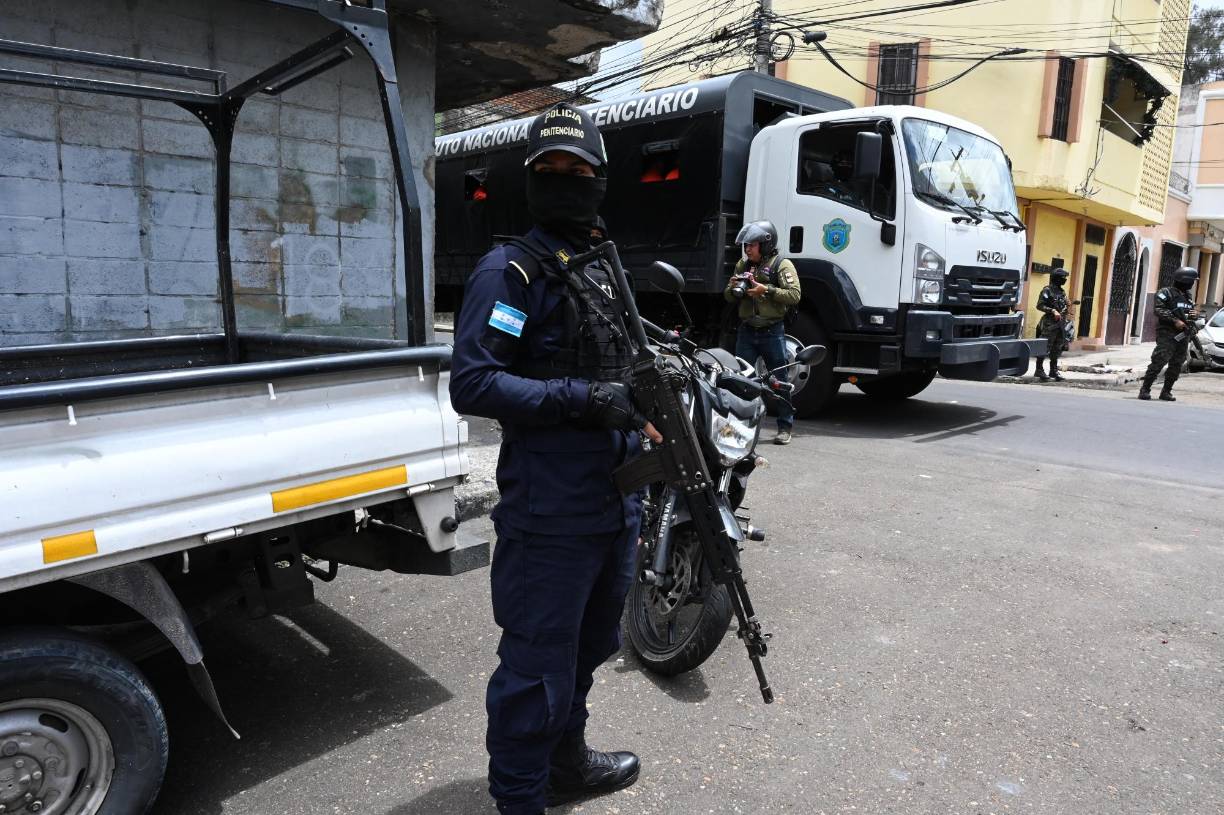 A prison guard watches inmates (out of frame) as they erase graffiti alluding to the Barrio 18 and Mara Salvatrucha (MS-13) gangs in Tegucigalpa on July 8, 2024. Inmates held in the Tamara National Penitentiary Center, 20 km north of the capital, went out handcuffed to erase graffiti as part of their social reinsertion. (Photo by Orlando SIERRA / AFP)