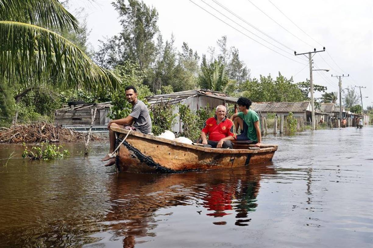 Tres hombres navegan en un bote para ofrecer ayuda ante las intensas lluvias y algunas penetraciones del mar en zonas costeras bajas en el occidente de Cuba tras el paso del huracán Helene al oeste de la isla.