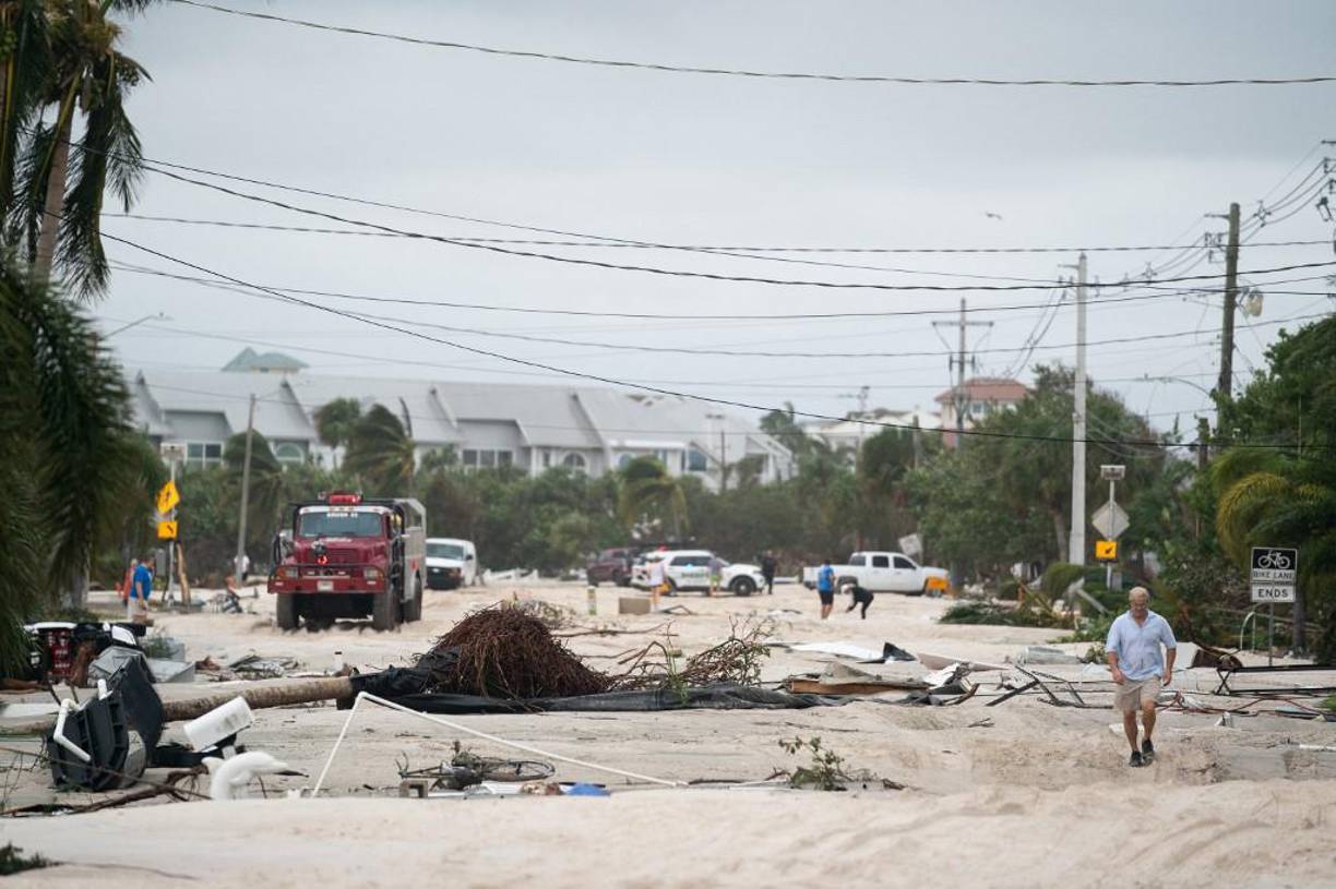 La gente regresa a una calle cubierta de arena dañada por el huracán Ian en Bonita Springs, Florida.