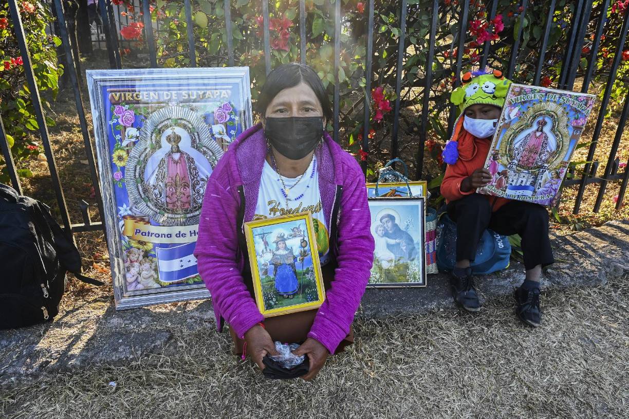 Maura Isabel López y su nieto sostienen carteles que representan a la Virgen de Suyapa, patrona de Honduras,.