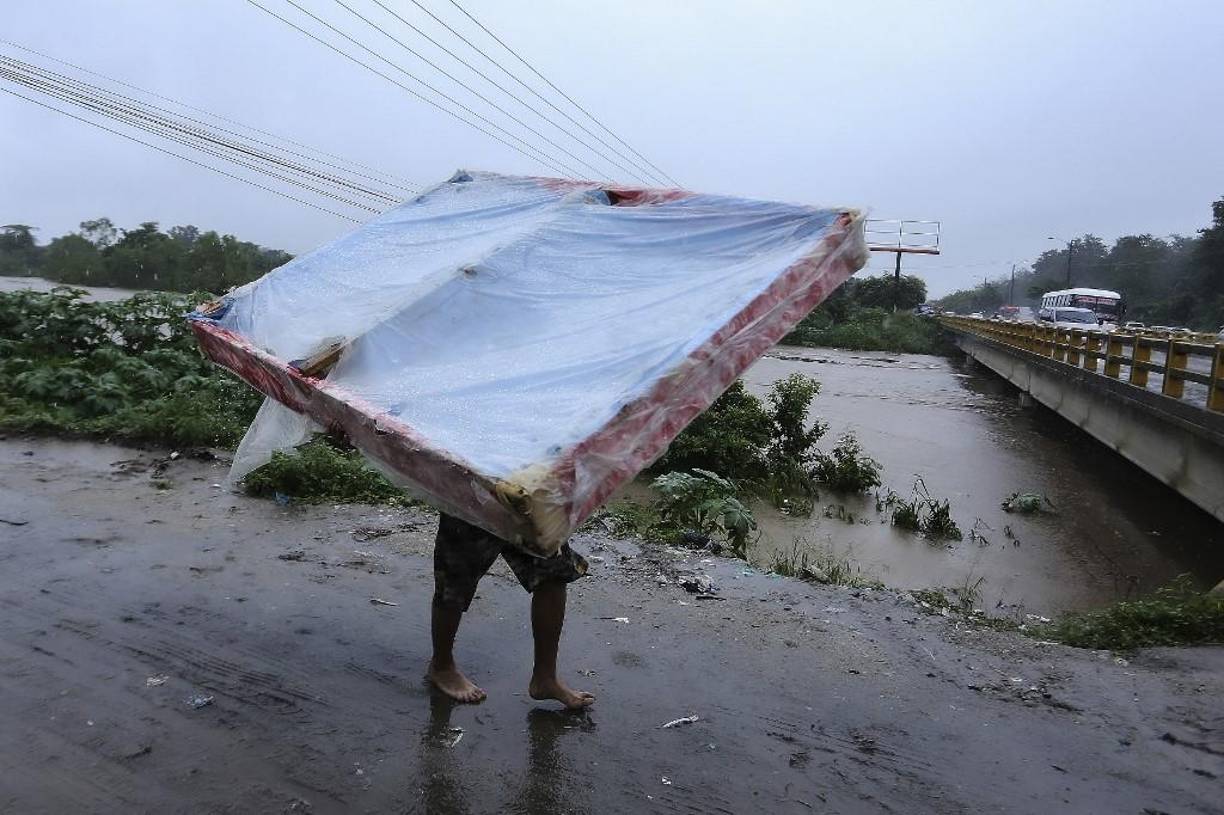 Un residente de La Lima se monta su cama al hombro para evitar perderla por la inundaciones en el sector.