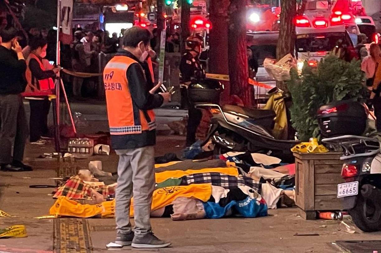 Los cuerpos de las víctimas, que se cree que sufrieron un paro cardíaco, están cubiertos con mantas en el popular distrito de vida nocturna de Itaewon en Seúl .