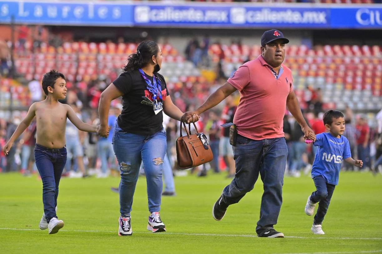 Impactante imagen. Familia huye de la violencia en el estadio La Corregidora, durante la batalla campal entre hinchas de Atlas y Querétaro. Los padres optaron por quitarle la camiseta al niño para que los rivales no los agredan.