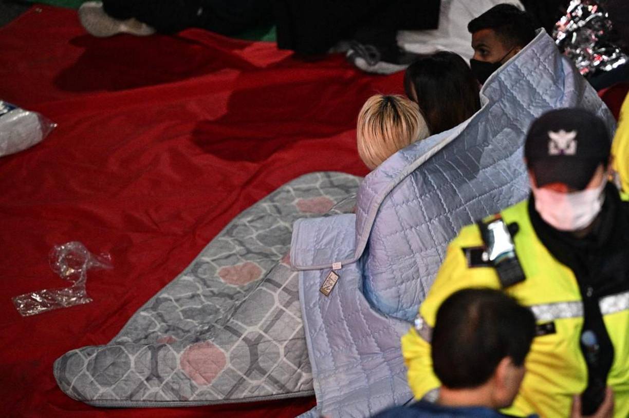 La gente se sienta envuelta en mantas después de que decenas murieran en Seúl, Corea del Sur.
