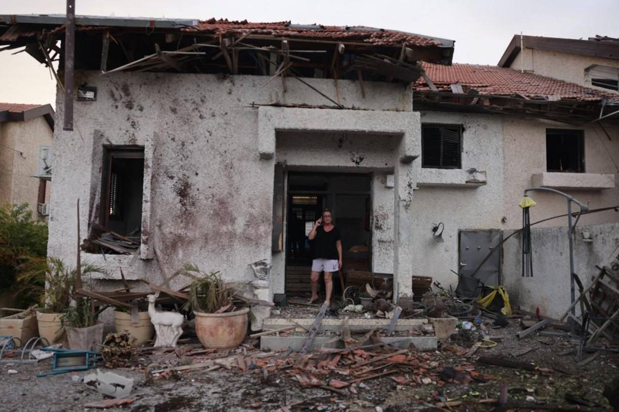  Una mujer se encuentra en la entrada de una casa dañada en la ciudad de Ashkelon, en el sur de Israel, después de un ataque con cohetes desde Gaza el 9 de octubre de 2023. 