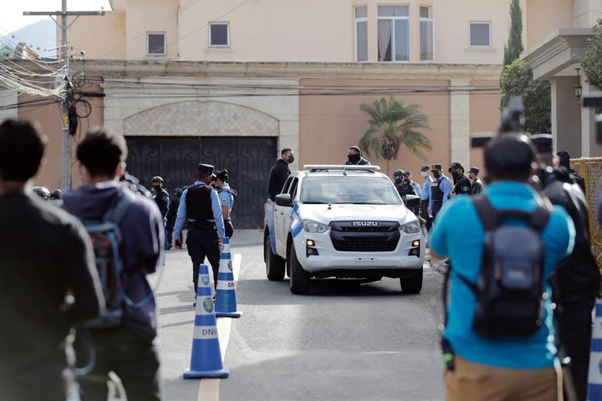 Agentes de policía y periodistas esperan en las afueras de la casa del expresidente Juan Orlando Hernández hoy, en Tegucigalpa.