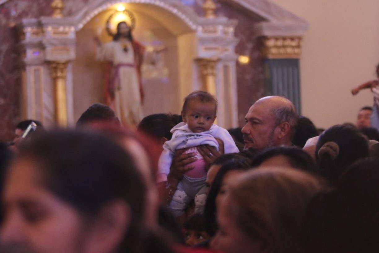 Un feligrés católico carga a un bebé en la misa en honor a la Virgen de Suyapa.